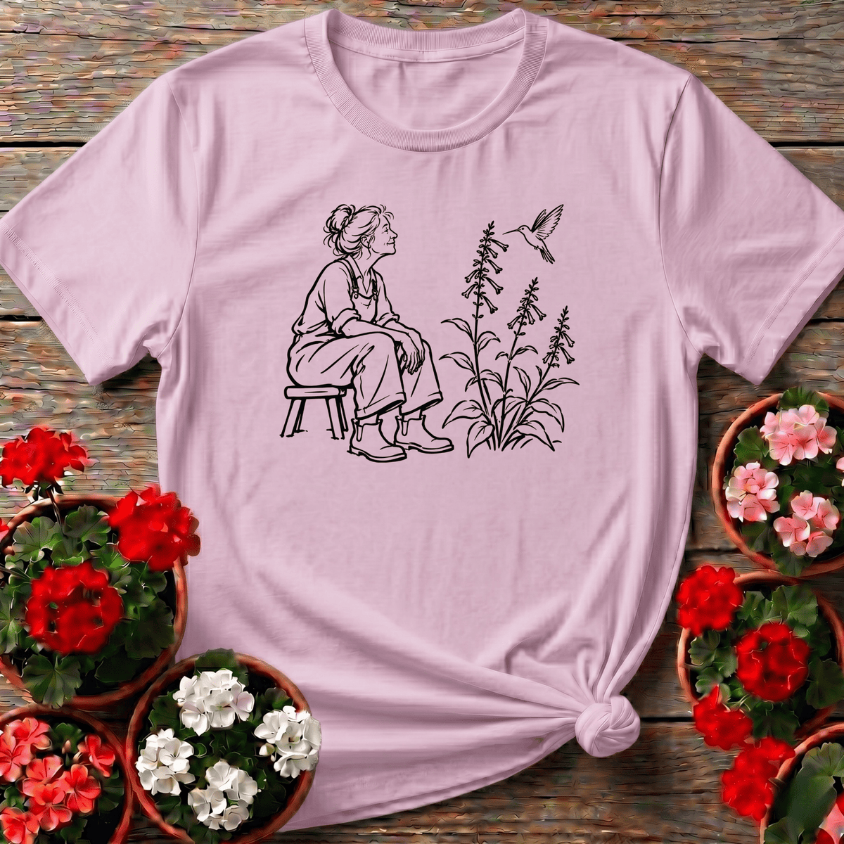 Light Pink soft line art gardening tee with hand-drawn woman in garden boots watching a hummingbird for her